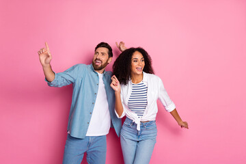 Young couple enjoying time together, celebrating and posing in casual attire against a pink background