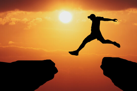 Leap of Faith: A silhouette of a determined man leaping across a chasm, bathed in the golden light of a setting sun, symbolizing the courage and determination needed to overcome challenges.  