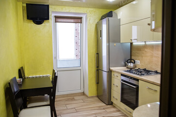 Modern kitchen with yellow walls and stainless steel appliances in a cozy apartment
