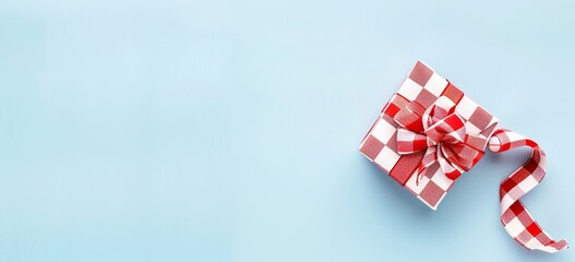 Fototapeta premium Red checkered Christmas gift with candy cane on blue background