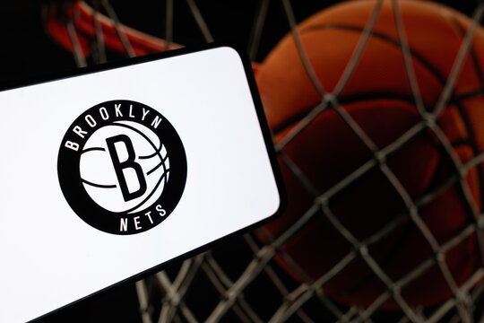 London, UK, 01.30.2025: Brooklyn Nets basketball team logo on phone screen with basketball net background