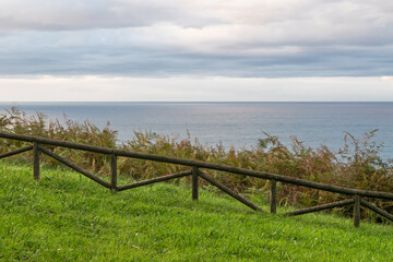 Marine horizon behind a fence on the cliff. Cloudy day