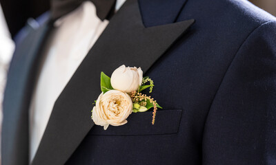 Man wearing a black suit with a white shirt and a flower on his lapel