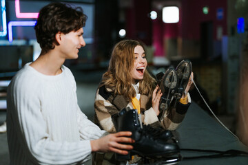 Young adults enjoying ice skating activity while holding skates indoors