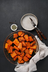 Baked pumpkin with herbs on a glass dish top view black table. Autumn Vegetable Dishes. High quality photo