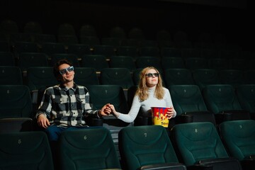 Couple enjoying a movie night while holding hands and sharing popcorn
