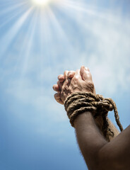 Rope tied hands on sky background