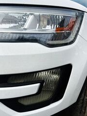 Obraz premium Closeup of a car headlight and grille on a white vehicle