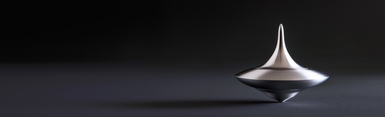 Fototapeta premium A sleek metal spinning top in motion on a dark textured surface, with a dramatic black background. Balance and uncertainty concept. Ideal for desktop wallpaper background. Copy space.