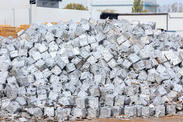 tacks of pressed aluminum cubes glisten in bright light, hinting at large-scale recycling operations. Reflective surfaces highlight an industrial push toward sustainability and efficient resource use