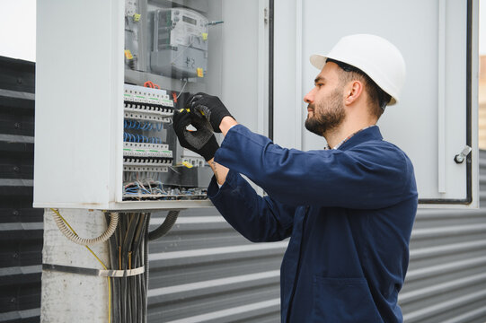A male electrician works in a switchboard