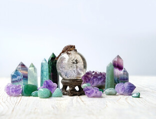 little toad on magic crystal ball and different minerals on wooden table close up. Witchcraft,...