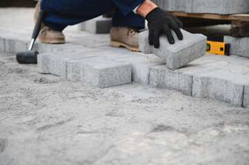 The master in gloves lays paving stones in layers. Garden brick pathway paving by professional...