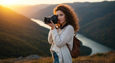 Obraz premium A young female travel photographer with curly brown hair and blue eyes, standing on a scenic hilltop during golden hour