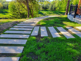 In the spring park, a path made of concrete rectangles is laid between the trees. The concept of...