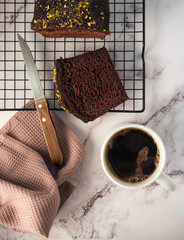 Cup of coffee and one slice of cake on a white marble counter. 