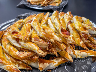 baked ham and cheese rolls, finger food appetizers on black napkin in silver tray, close up