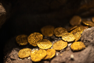 Ancient gold coins from the colonial era scattered over large rocks, resembling a lost treasure....