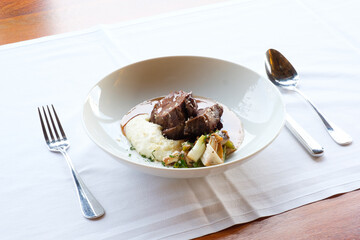 Braised meat with creamy polenta and sauteed vegetables