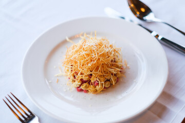 A culinary creation: small pasta topped with crispy fried strands and grated cheese