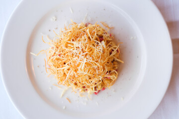 Crispy fried potato strands atop a savory dish garnished with grated cheese and pepper