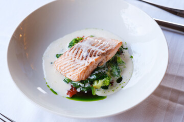 Pan seared salmon fillet served atop a bed of sauteed greens in a creamy sauce