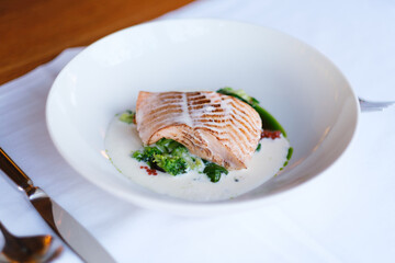 Grilled fish fillet served with creamy sauce and sauteed greens