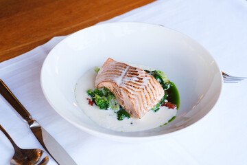 Pan seared fish fillet served with creamy sauce and sauteed greens