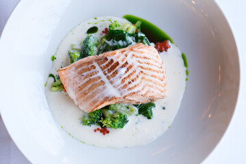 Pan seared salmon fillet served with creamy sauce broccoli and spinach