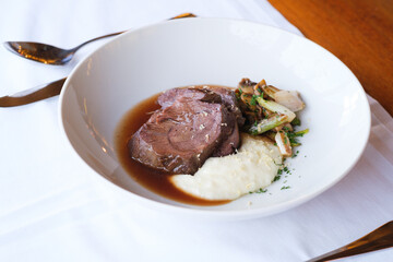 Seared meat slices served with creamy purée and sautéed vegetables