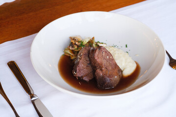 Savor this elegant plated dish: tender meat creamy mashed potatoes and sautéed vegetables