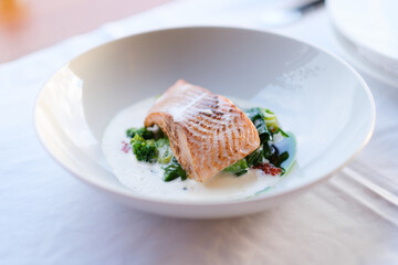 Pan seared salmon fillet served with creamy sauce and sautéed greens