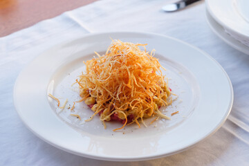 A culinary delight: a vibrant dish topped with crispy golden strands