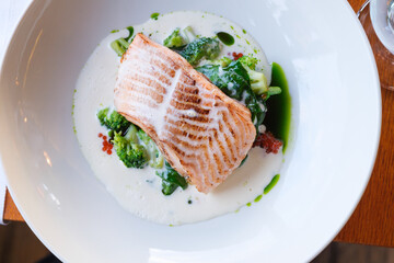 Pan seared salmon fillet atop creamy sauce with sauteed broccoli and spinach