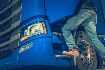 Worker Climbs Into Blue Semi Truck During Daylight at a Loading Dock