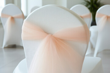 Peach Tulle Chair Sashes: Elegant peach tulle sashes elegantly adorn pristine white banquet chairs, creating a refined and romantic ambiance perfect for weddings or special events.  
