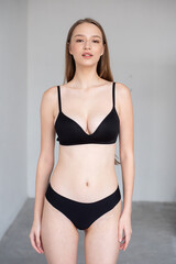 Obraz premium Professional modeling digitals of a young female model in black lingerie, standing confidently in a clean studio setting. Capturing natural beauty, symmetry, and elegance for agency submission