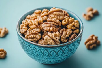 Fototapeta premium Fresh and tasty walnuts served in a decorative turquoise bowl against a soft blue background