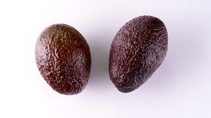 Two avocados are on a white background. They are brown and have a rough texture. Concept of freshness and naturalness, as avocados are a healthy and nutritious food