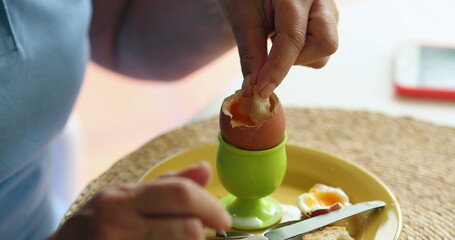 Person eating eating oeuf a la coque in the morning for breakfast