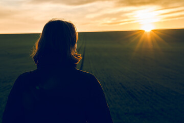 Fototapeta premium A girl contemplates the sunset in silence