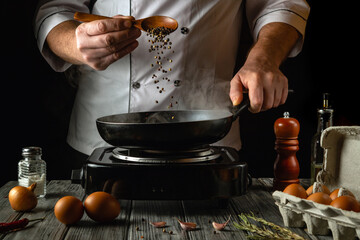 A skilled chef adds fresh peppercorns to a hot pan, releasing aromatic steam. The kitchen is lively...