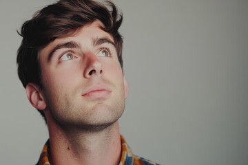 Obraz premium Thoughtful Young Man Gazing Upwards with Hopeful Expression