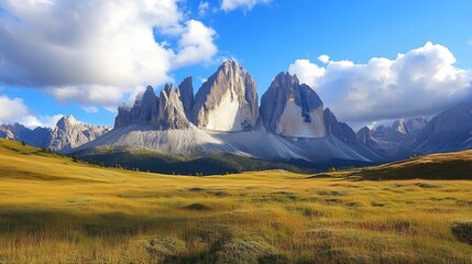 Fototapeta premium Stunning view of dramatic mountain peaks with lush green meadows and a vibrant blue sky with scattered clouds.