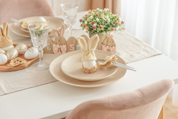 Festive Easter table setting with Easter bunny made from egg and knitted ears. Easter celebration concept