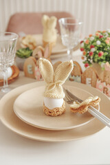 Close-up festive Easter table setting with Easter bunny made from egg and knitted ears. Easter celebration concept
