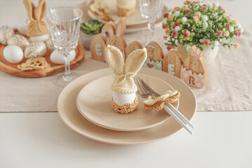 Festive Easter table setting with Easter bunny made from egg and knitted ears. Easter celebration concept