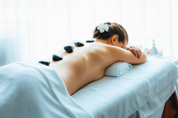 Hot stone massage at spa salon in luxury resort with day light serenity ambient, blissful woman...