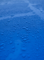 The image is of a blue surface with many small drops of water on it