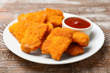 Delicious chicken nuggets with ketchup on wooden table, closeup